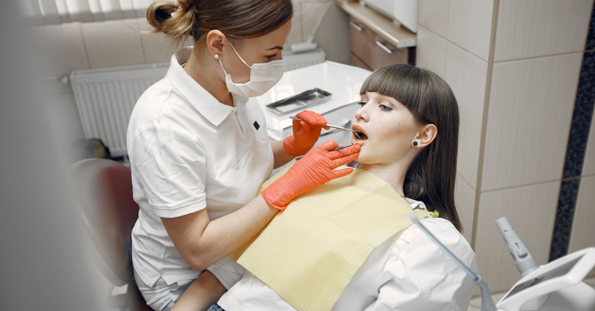 Dentist checking a young woman's front teeth in the dental chair