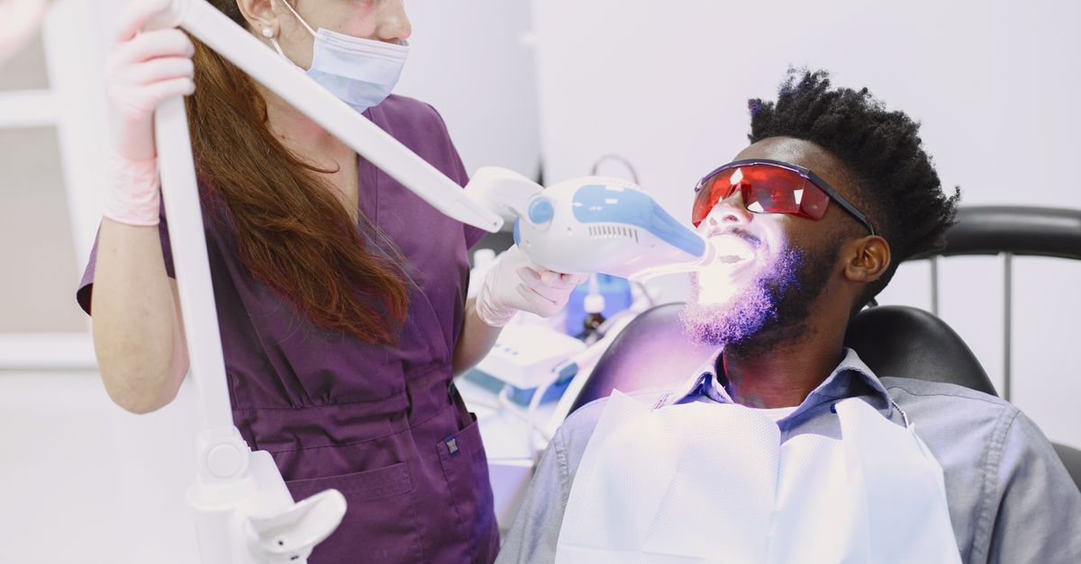 Dental professional performing in-office teeth whitening on a patient wearing protective glasses