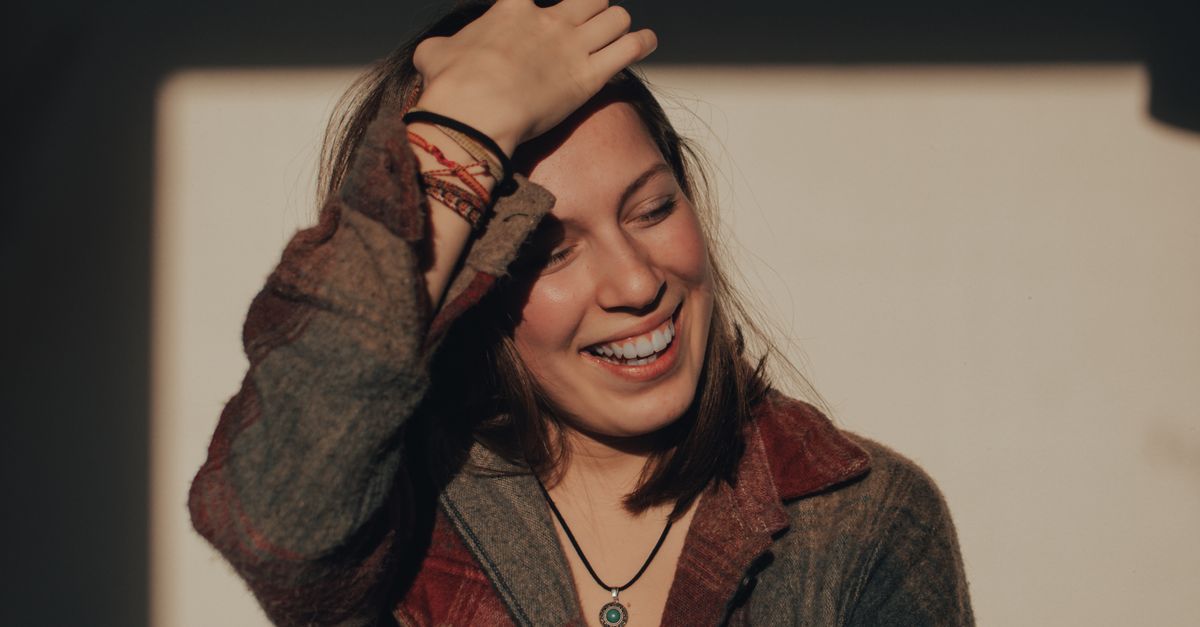 Woman laughing with a relaxed, natural smile in soft light