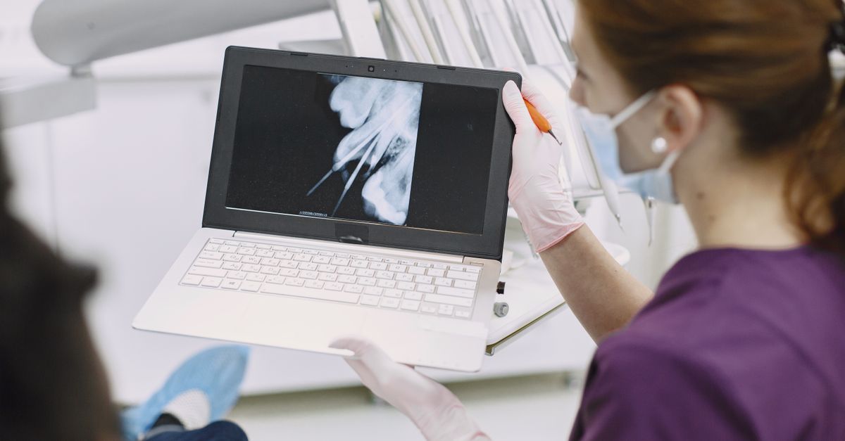 Dentist pointing to a dental X-ray on a laptop screen