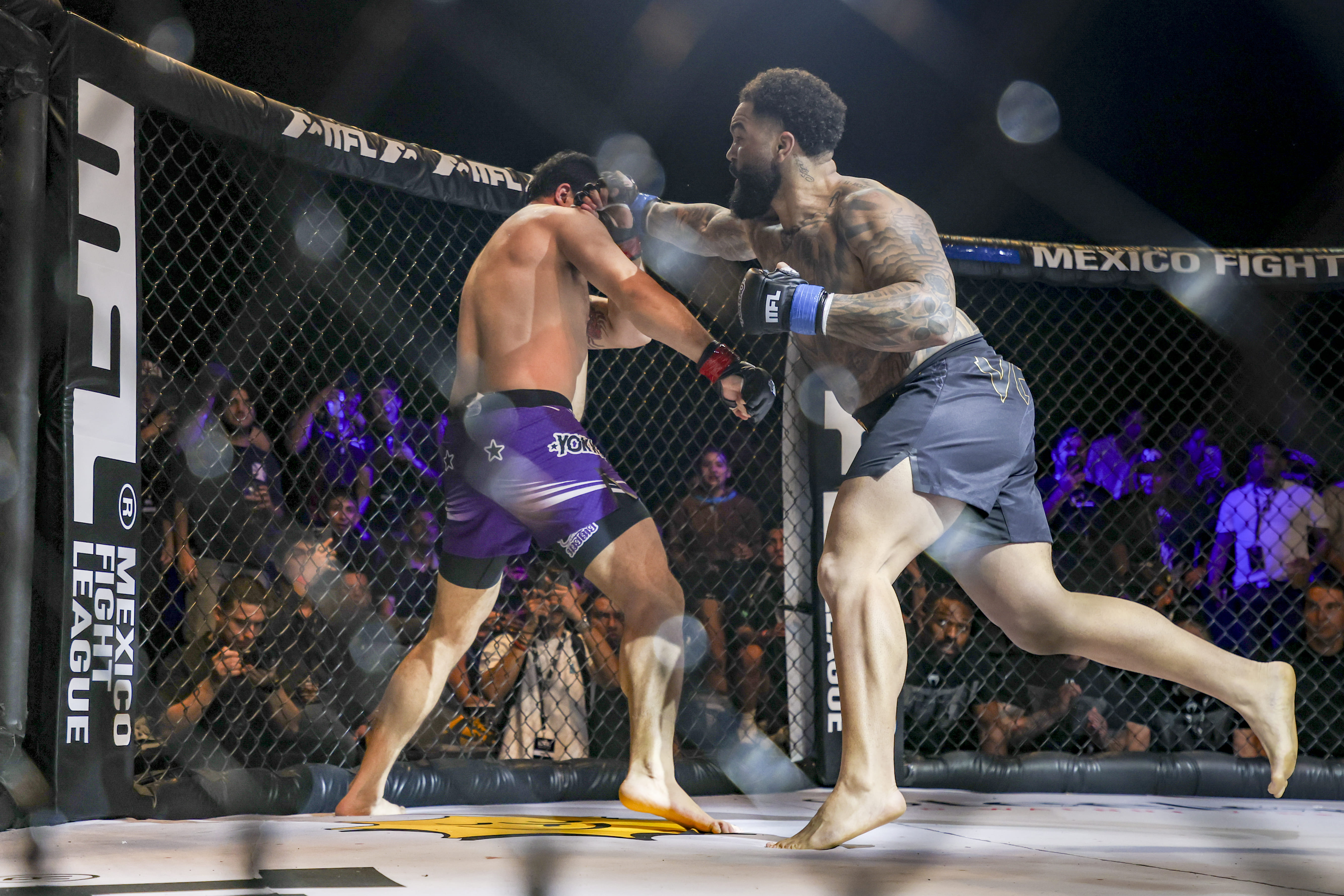 Dos peleadores de MMA en acción dentro del octágono, uno lanza un puñetazo al otro.