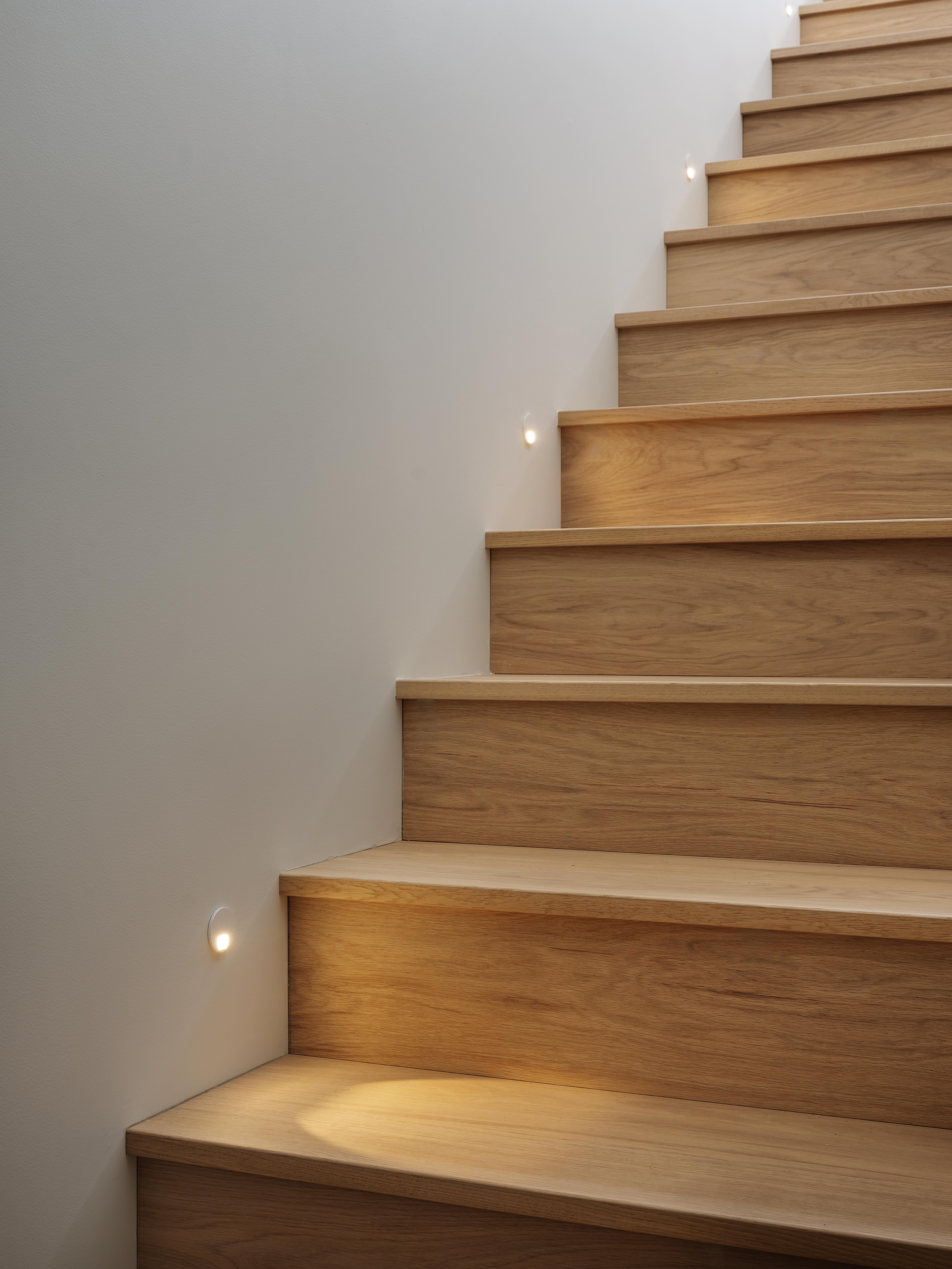 Cantilever house by Matt Deeb Architecture: Minimalist wooden staircase with small recessed wall lights illuminating each step.