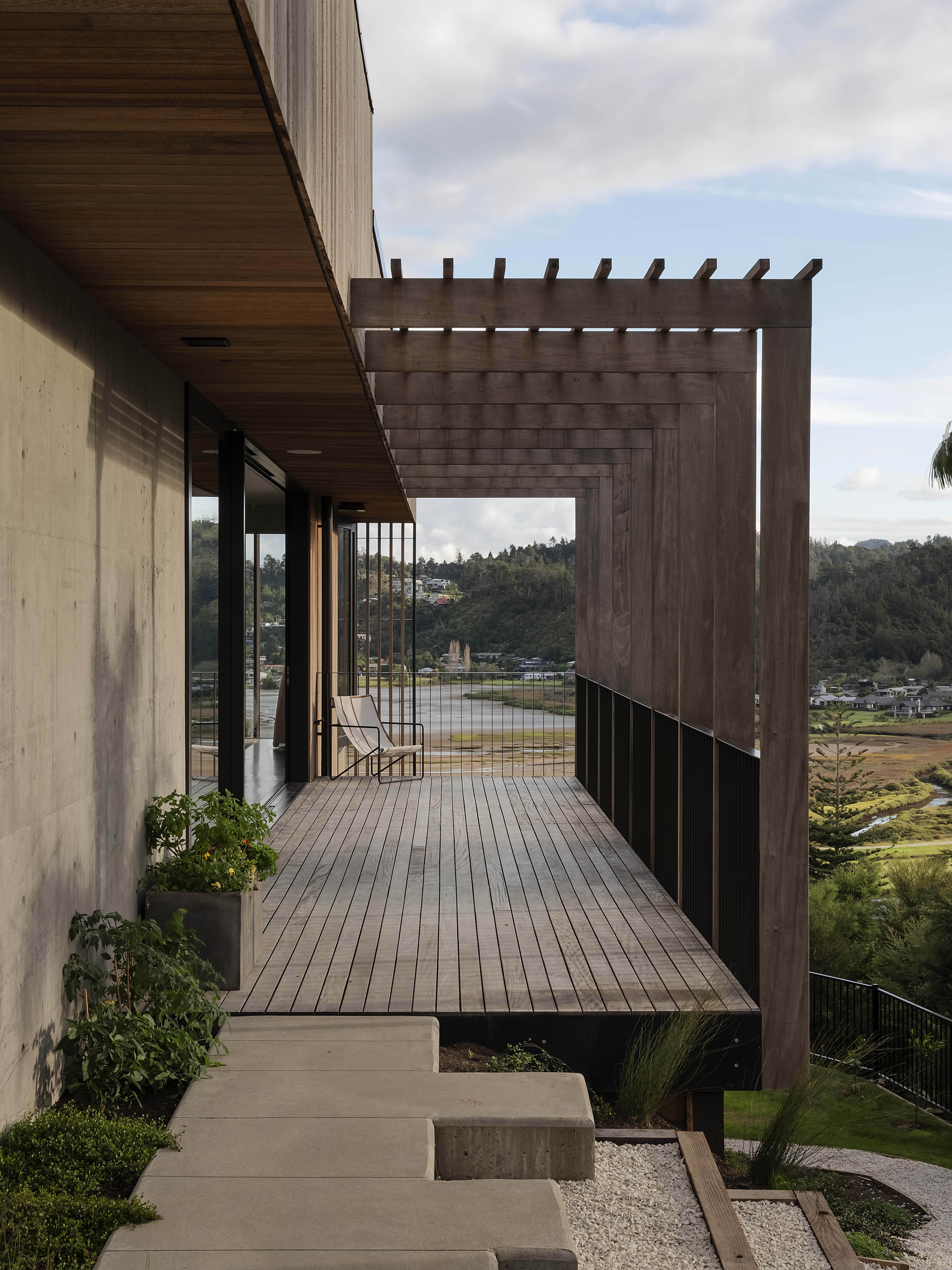 Paku Treehouse by Matt Deeb Architecture: Modern wooden cabin elevated on stilts surrounded by dense green trees and grass on a hillside.
