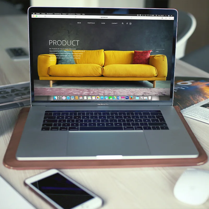 Laptop on desk with phone and notebook beside it.