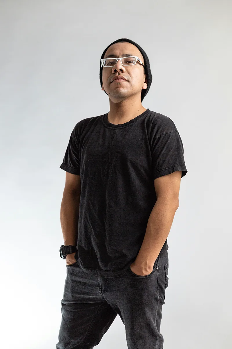 Portrait of a man in black t-shirt smiling against neutral background.