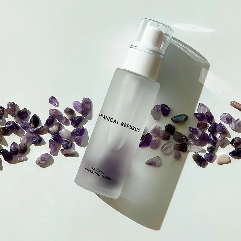 Silver spray bottle surrounded by purple decorative elements.