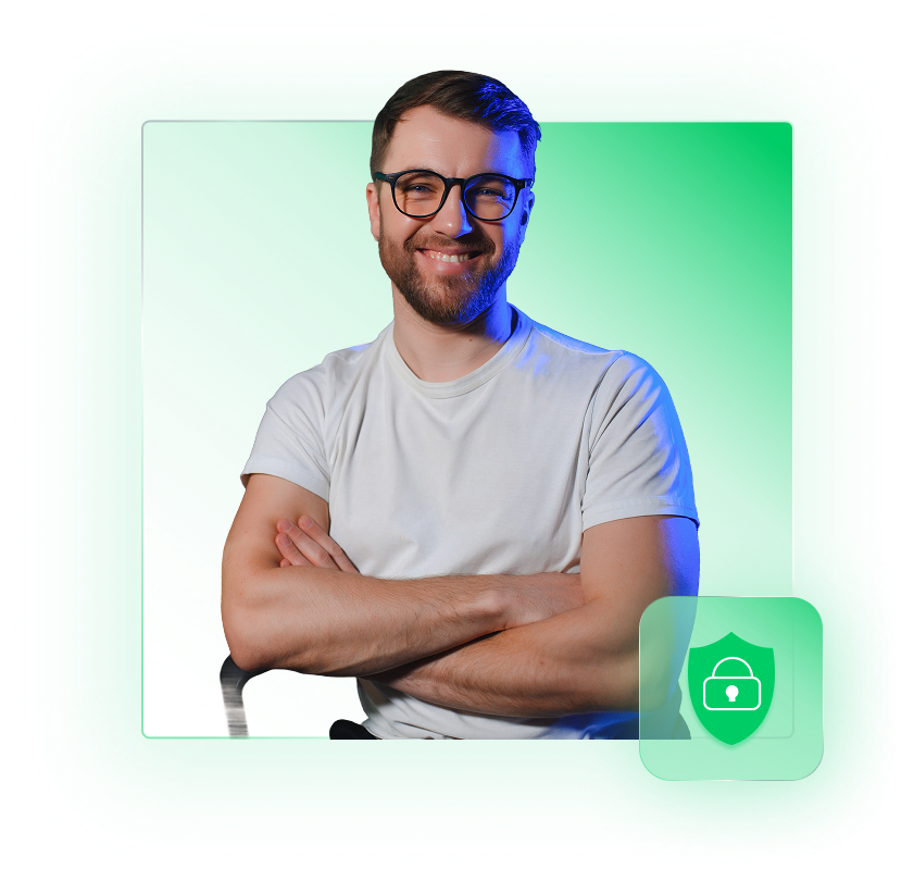 Smiling man with glasses and beard wearing a white t-shirt, sitting with arms crossed against a green gradient background.