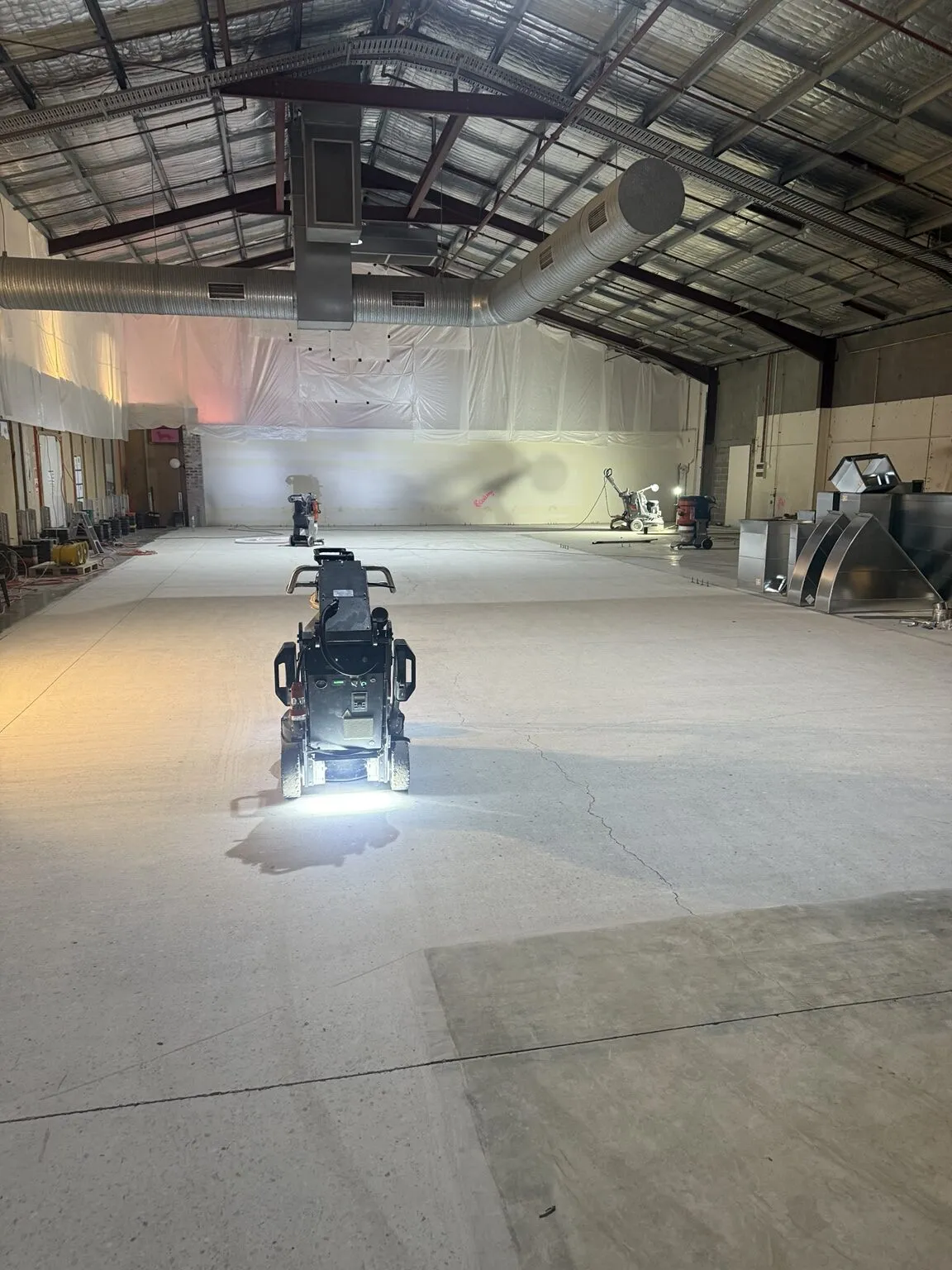 Commercial floor grinders preparing a large concrete area at an Orange Grove project.