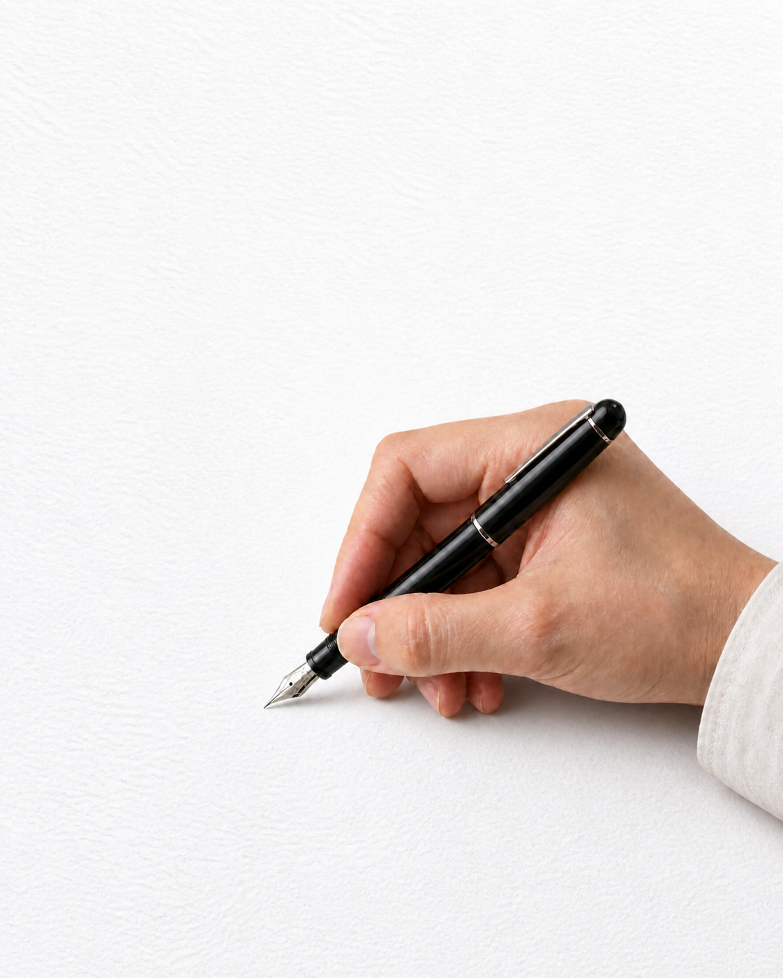 A hand writing on white textured paper with a black fountain pen