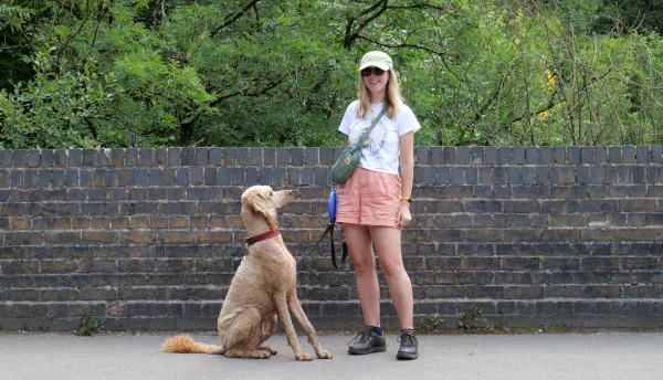 Rebecca from Trent Dog Walking walking outdoors with Omar, her curly-haired Poodle cross