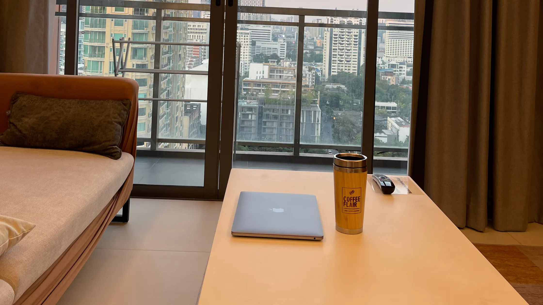 Afternoon remote work setup in a high-rise condo, Khet Watthana Bangkok, overlooking the city skyline.