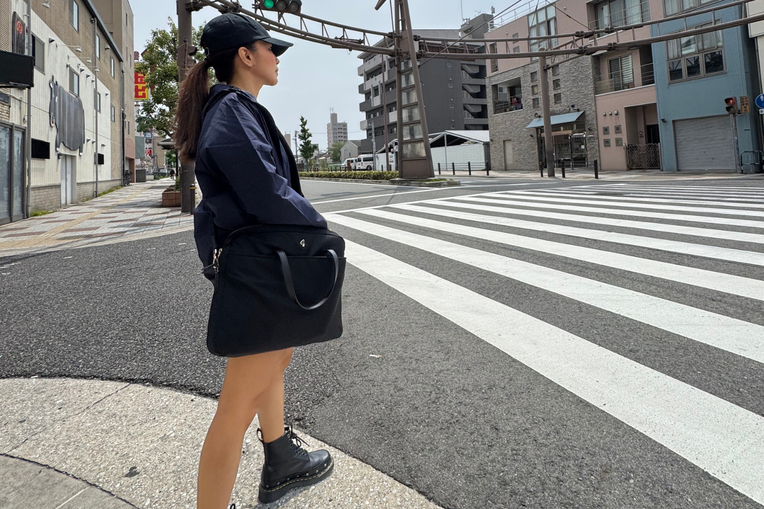 Remote worker in Osaka standing on road, waiting to cross toward nearby café.