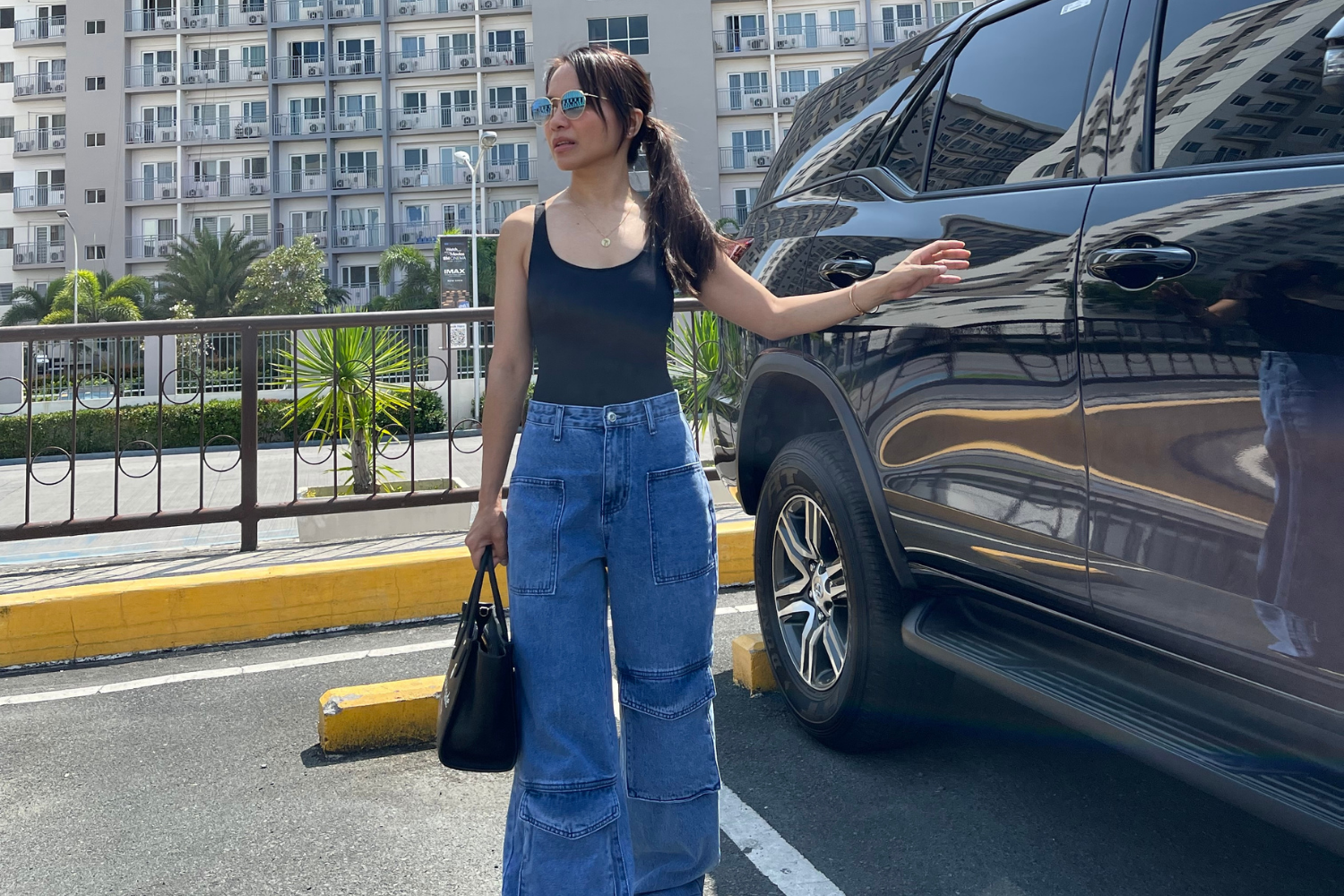 Woman standing beside SUV in a parking lot during Holy Week, enjoying a slow, peaceful day.