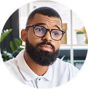 Man in glasses smiling thoughtfully, looking to the side.