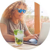 Woman wearing sunglasses enjoying a drink outdoors.