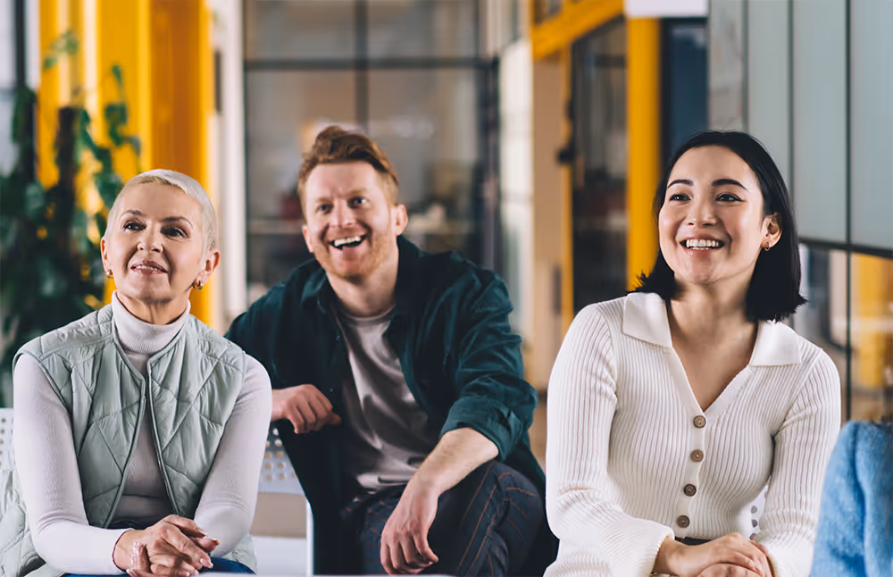 Group of professionals laughing and collaborating in office setting.
