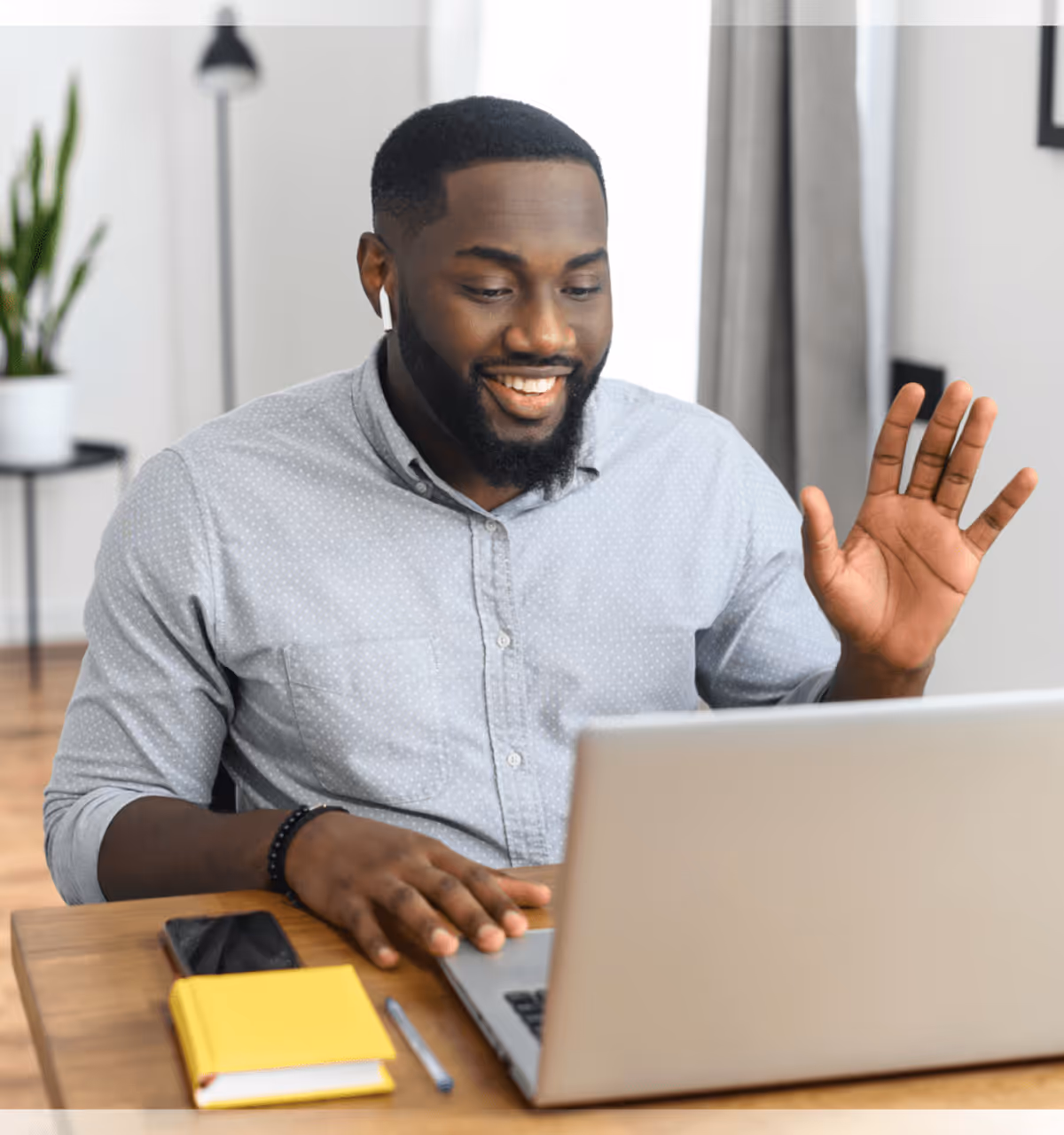 Man at home office desk gesturing while on video call.