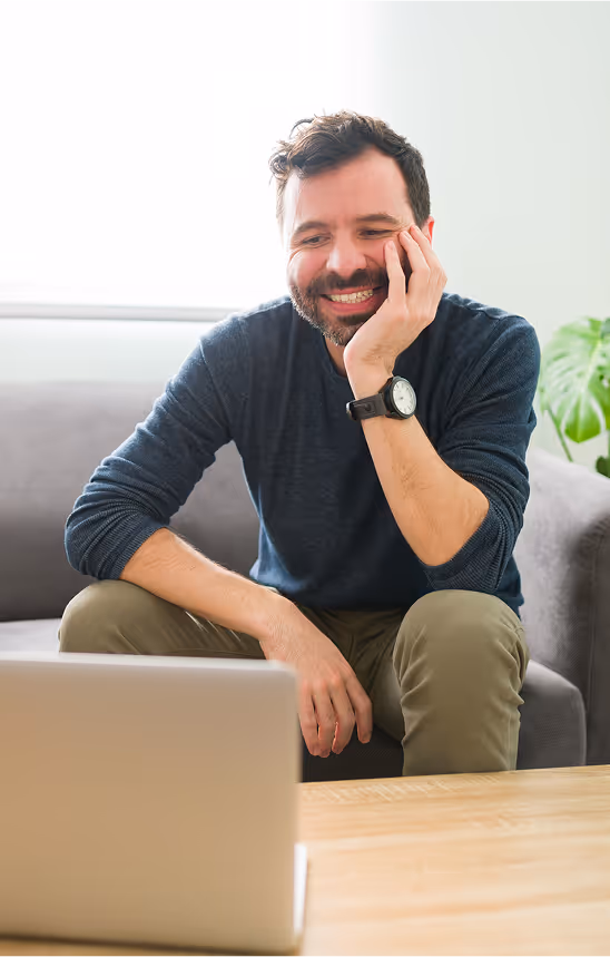 Smiling man sitting at a desk using a laptop.