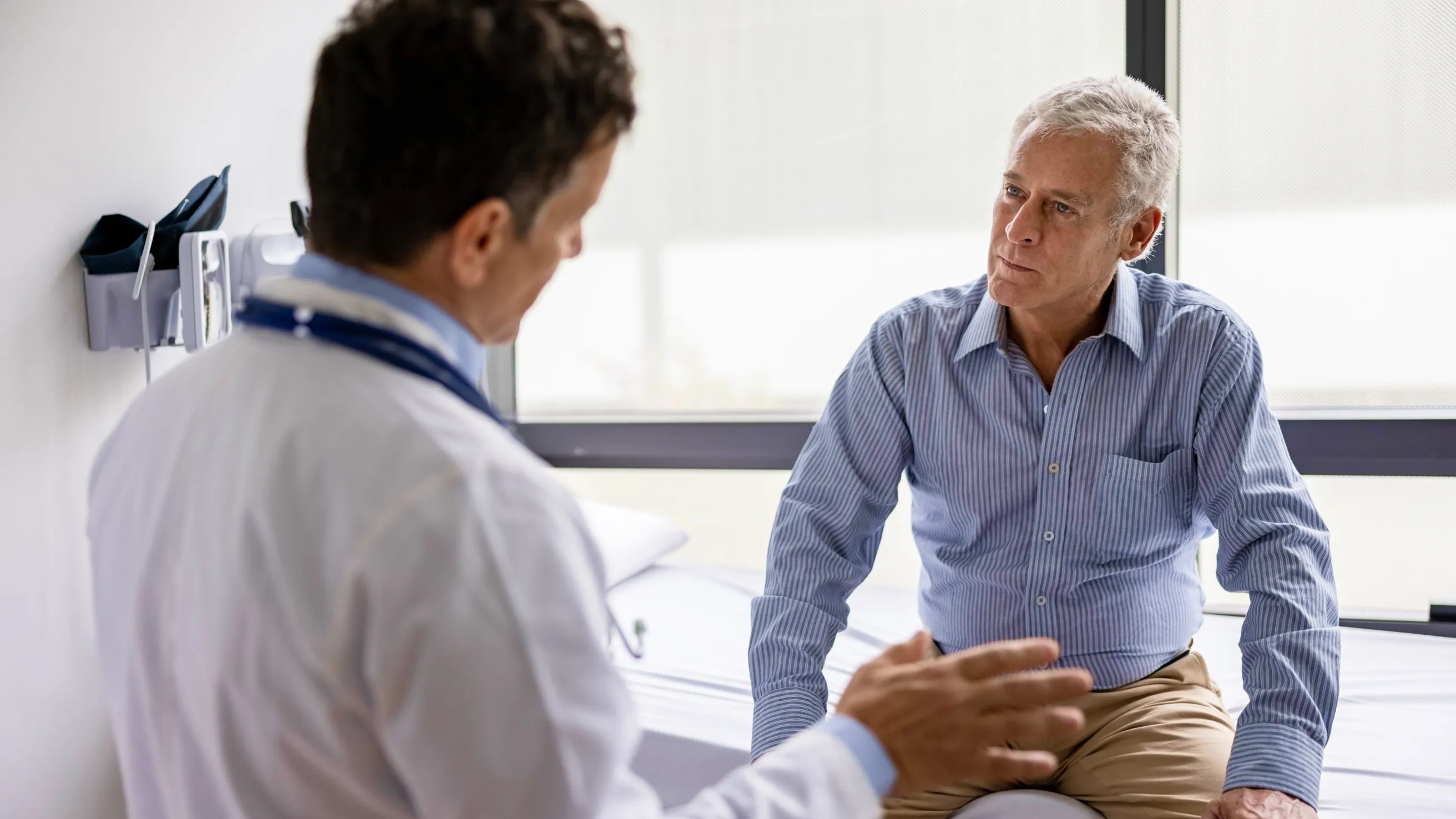 Doctor consulting with patient during medical appointment in exam room.