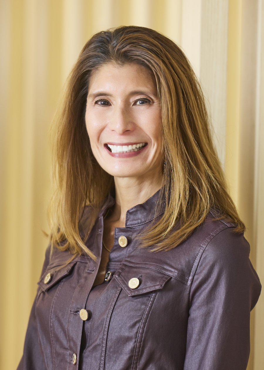 Professional headshot of smiling woman with long hair wearing a black top.
