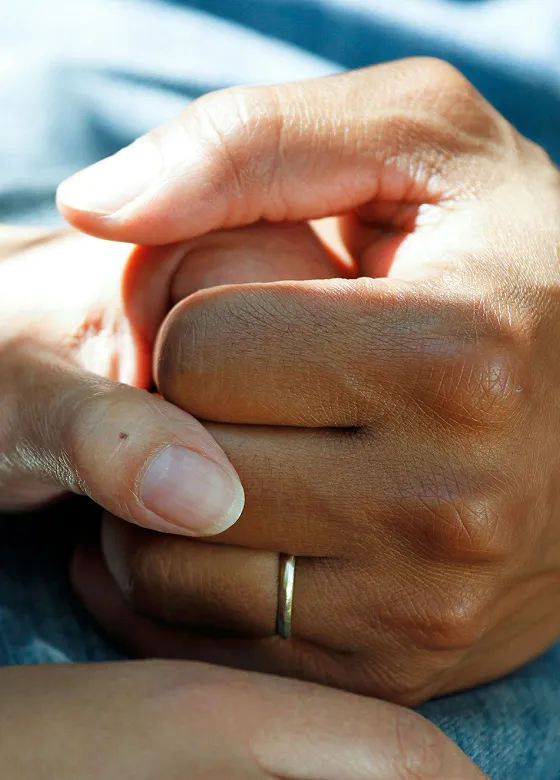 Close-up of two people holding hands in a comforting, supportive gesture.