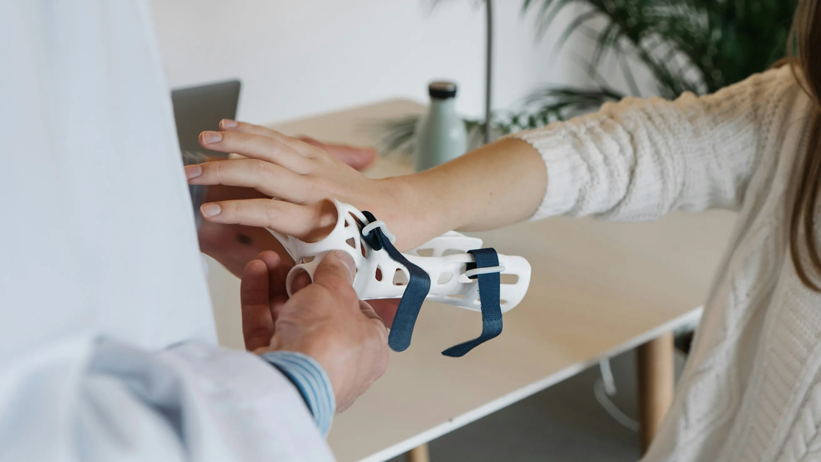 Doctor fitting a supportive hand brace on a patient during a rehabilitation appointment.
