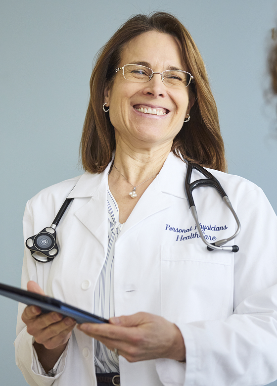 Doctor in white coat reviewing patient chart with stethoscope on desk.