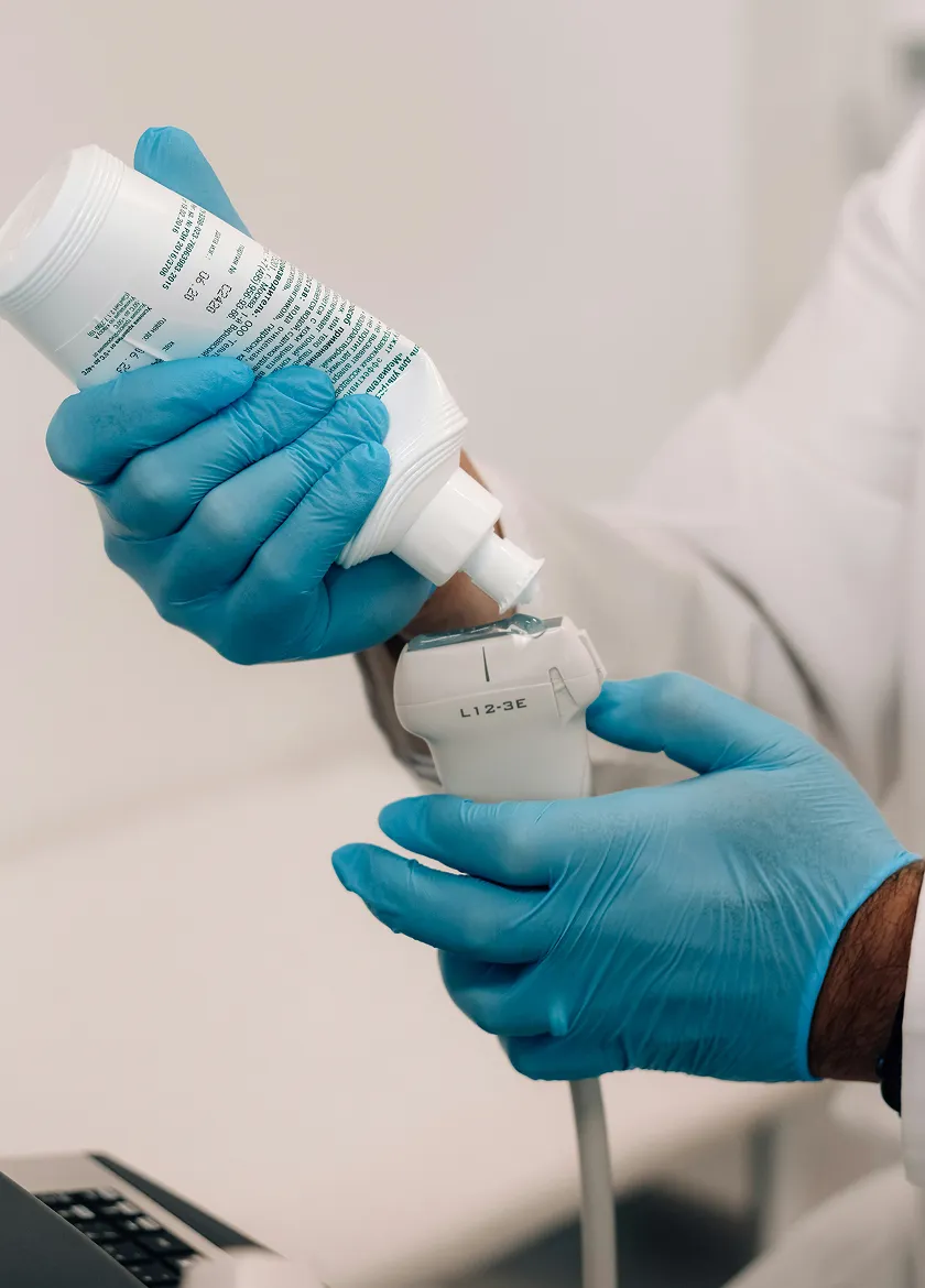 Healthcare professional applying ultrasound gel to medical device.