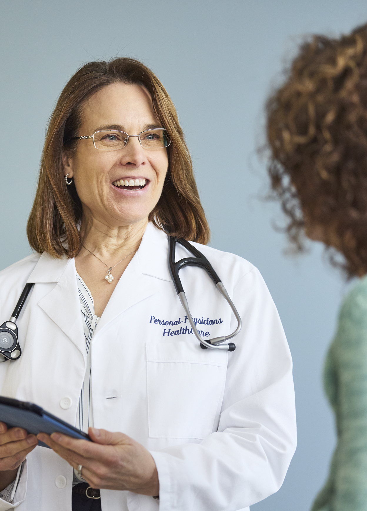 Smiling physician listening to patient during consultation.