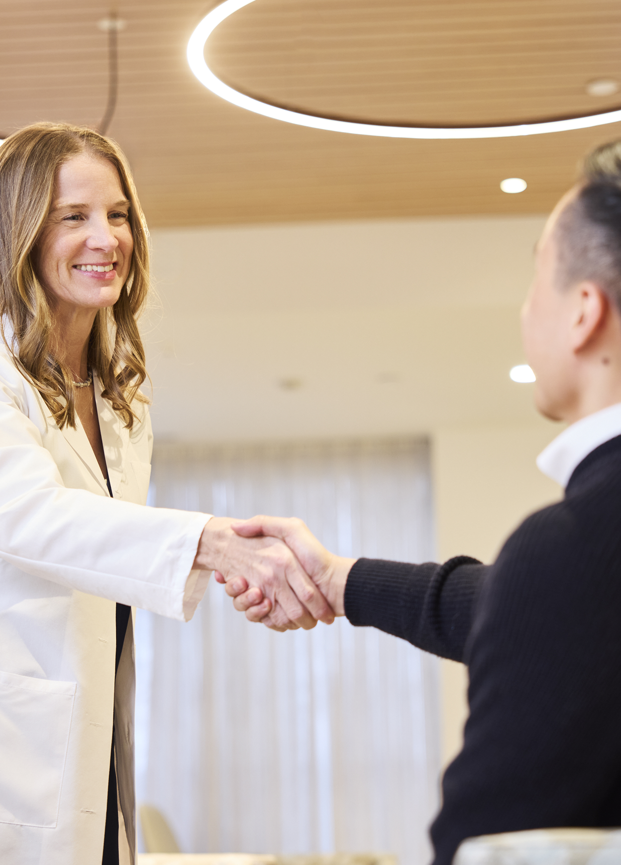 Doctor holding elderly patient’s hand during a supportive home care visit.