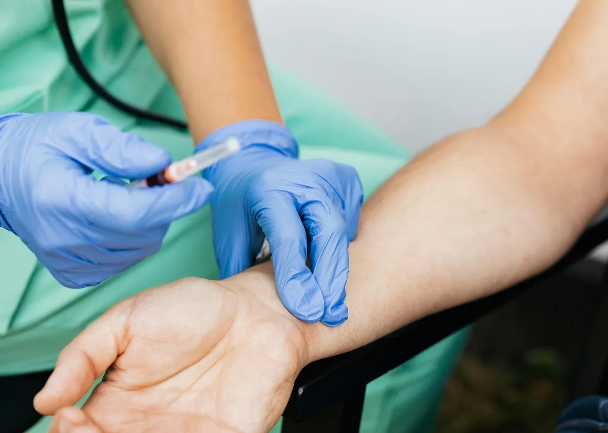 Nurse drawing blood from patient’s arm for lab testing.