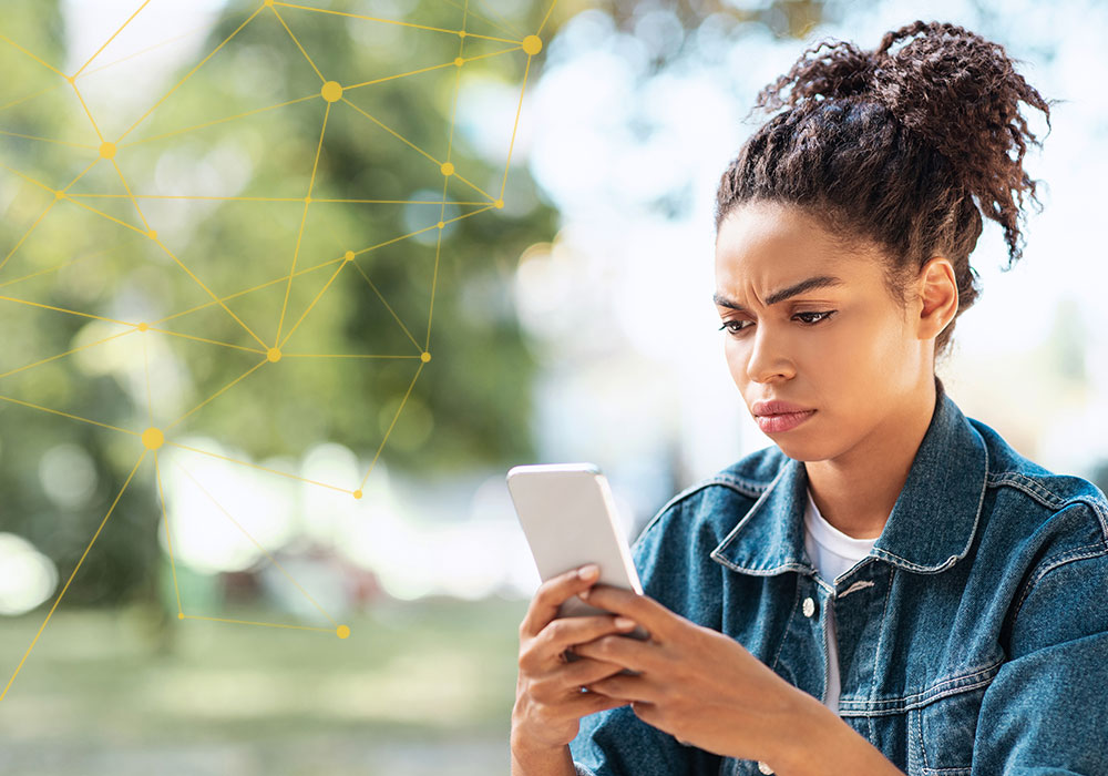 Woman looking concerned at smartphone with network overlay representing enterprise spoofing and data breach threats