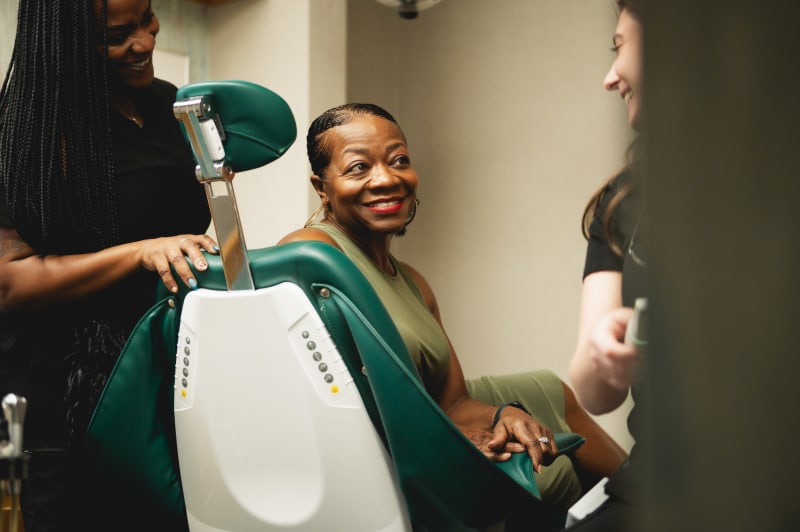 Dental team members smiling and engaging warmly with patient, showing friendly and welcoming practice culture