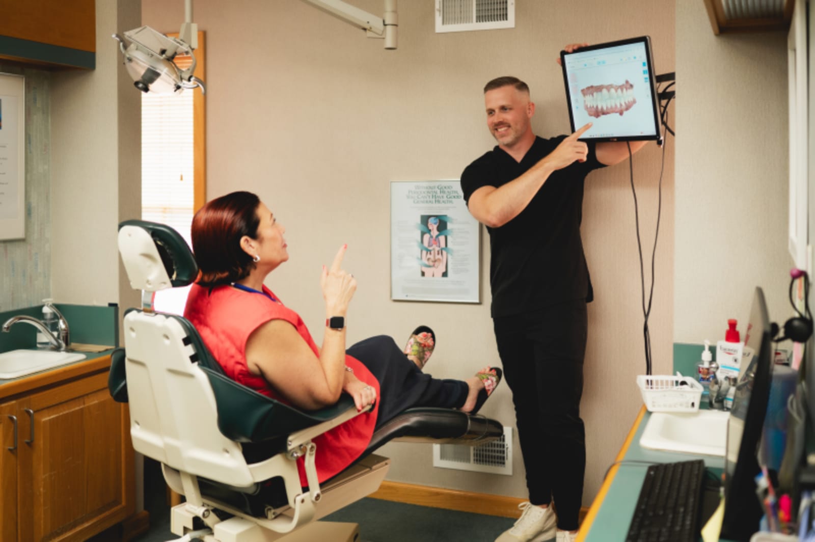 Dentist presenting dental model to seated patient during consultation and evaluation
