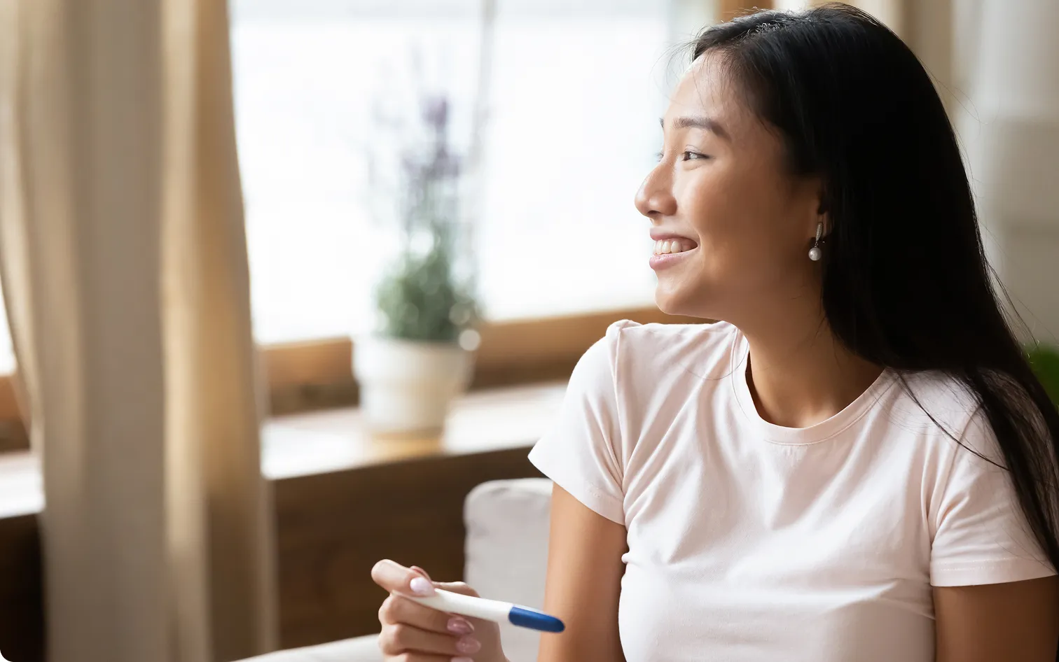 a woman smiling holding a pregnancy test