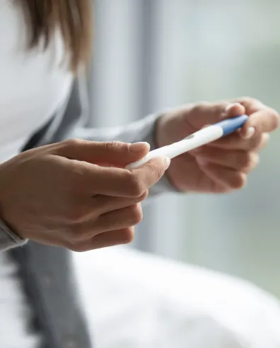 Person holding and looking at a pregnancy test.