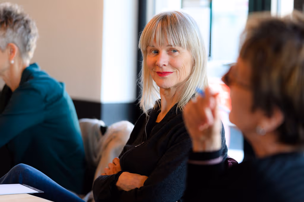 Foto van een vrouw die deelneemt aan een meeting en luistert naar een collega