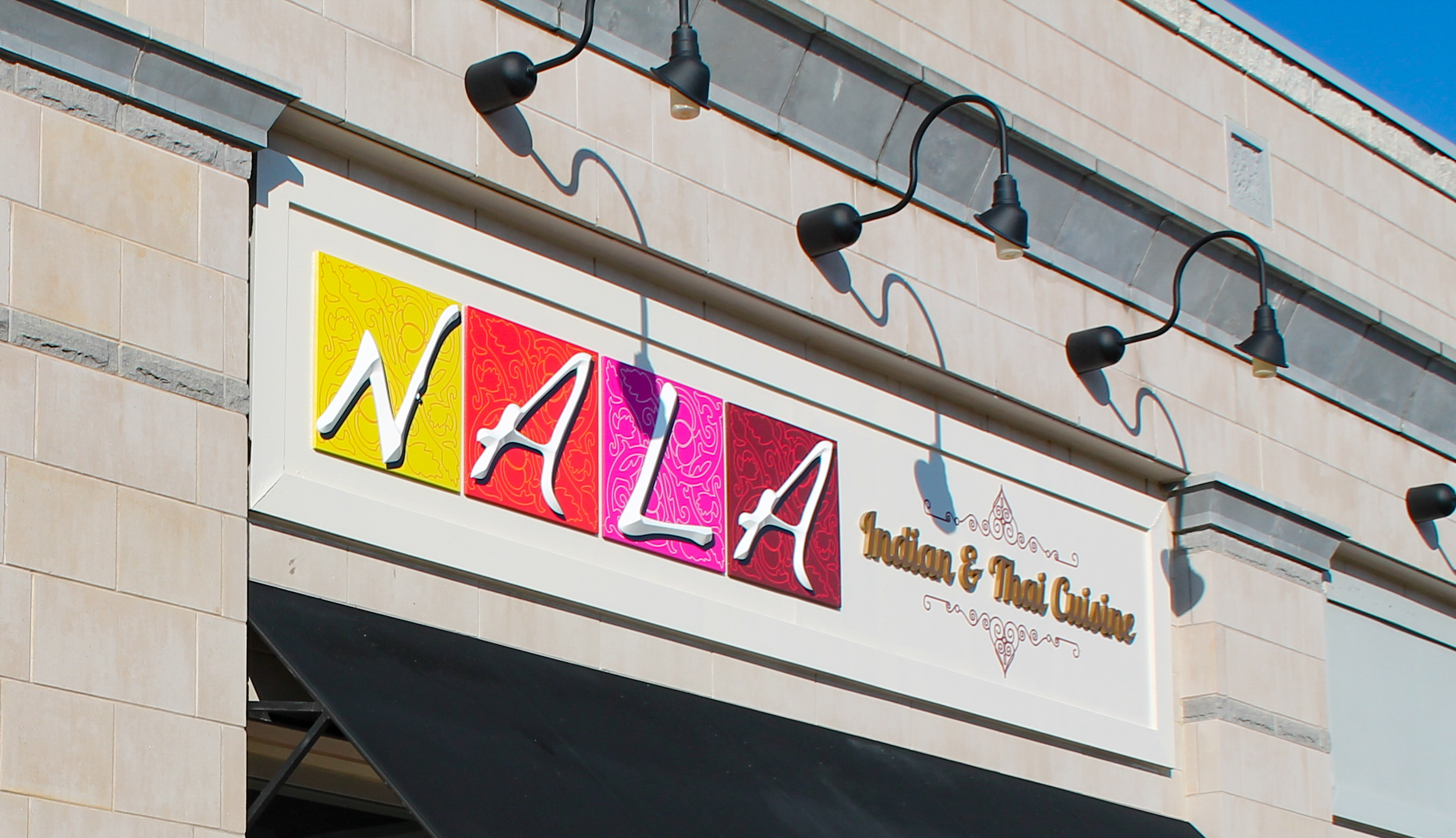 Dimensional letter sign lit with overhead gooseneck lamps