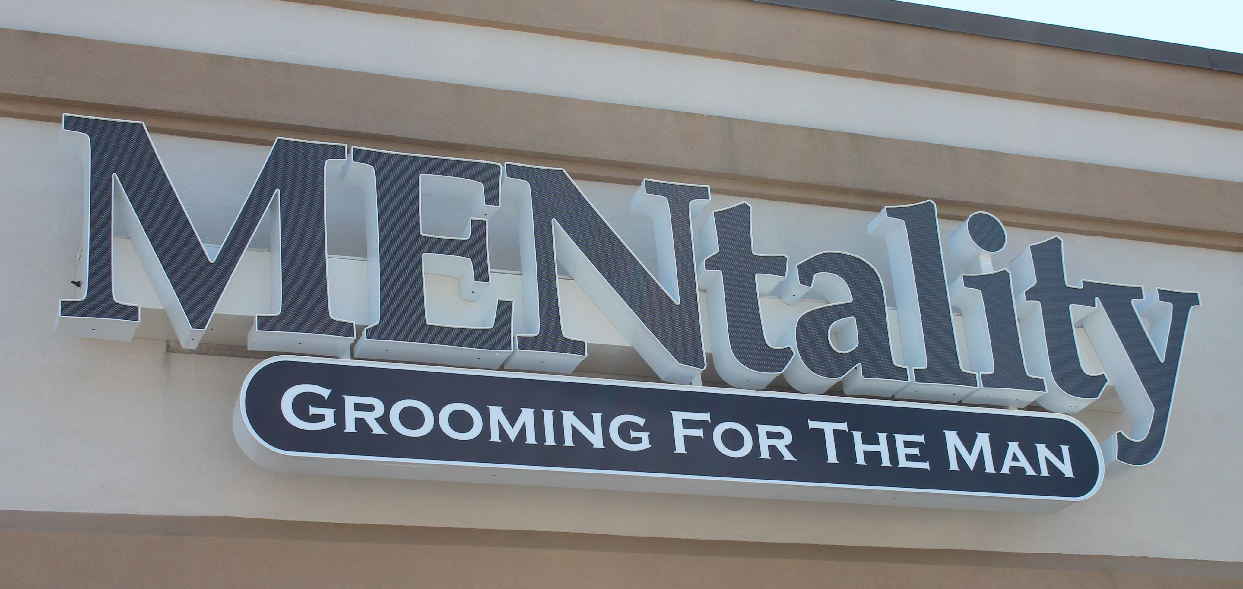 Navy blue channel letters above a barber's storefront