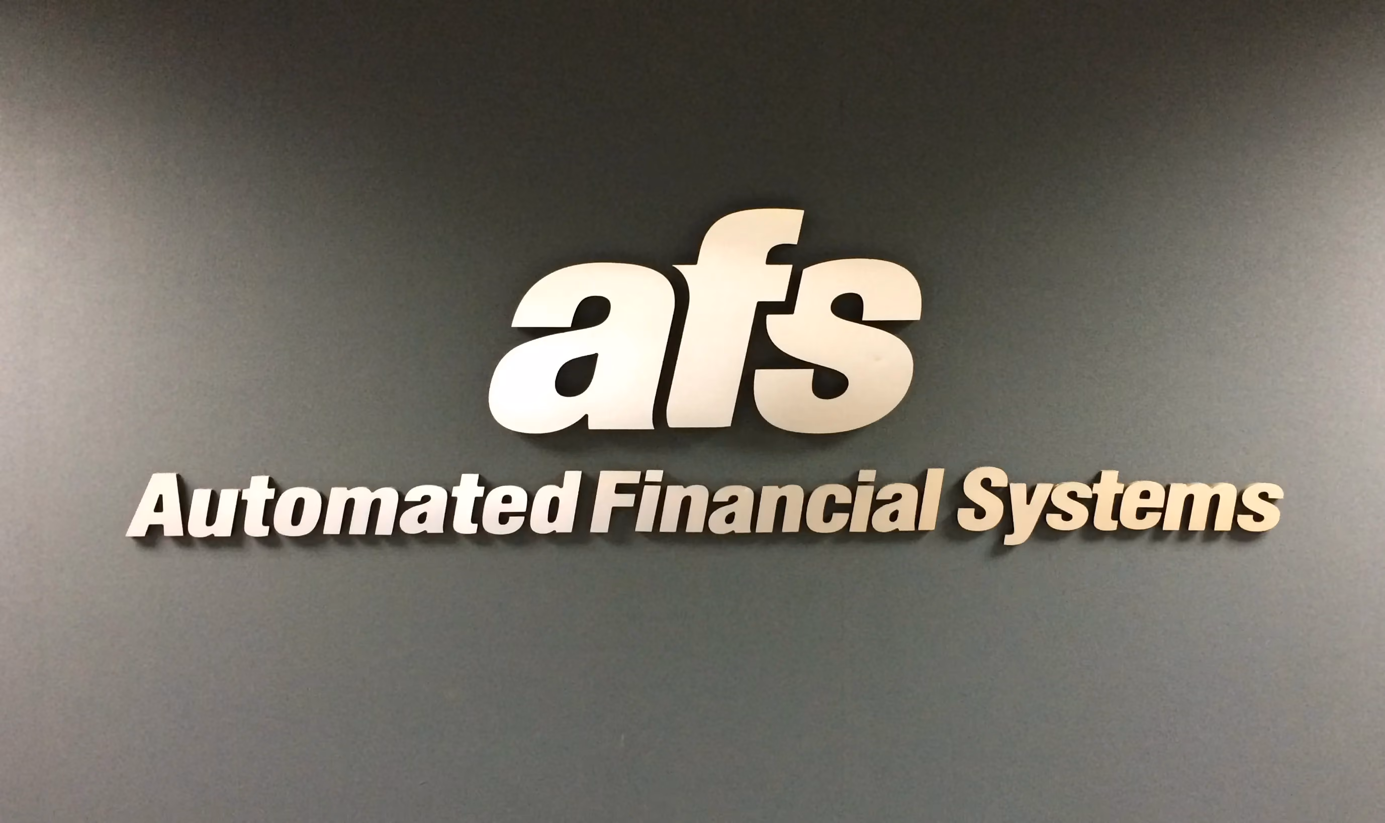 Brushed aluminum dimensional letters installed a gray wall