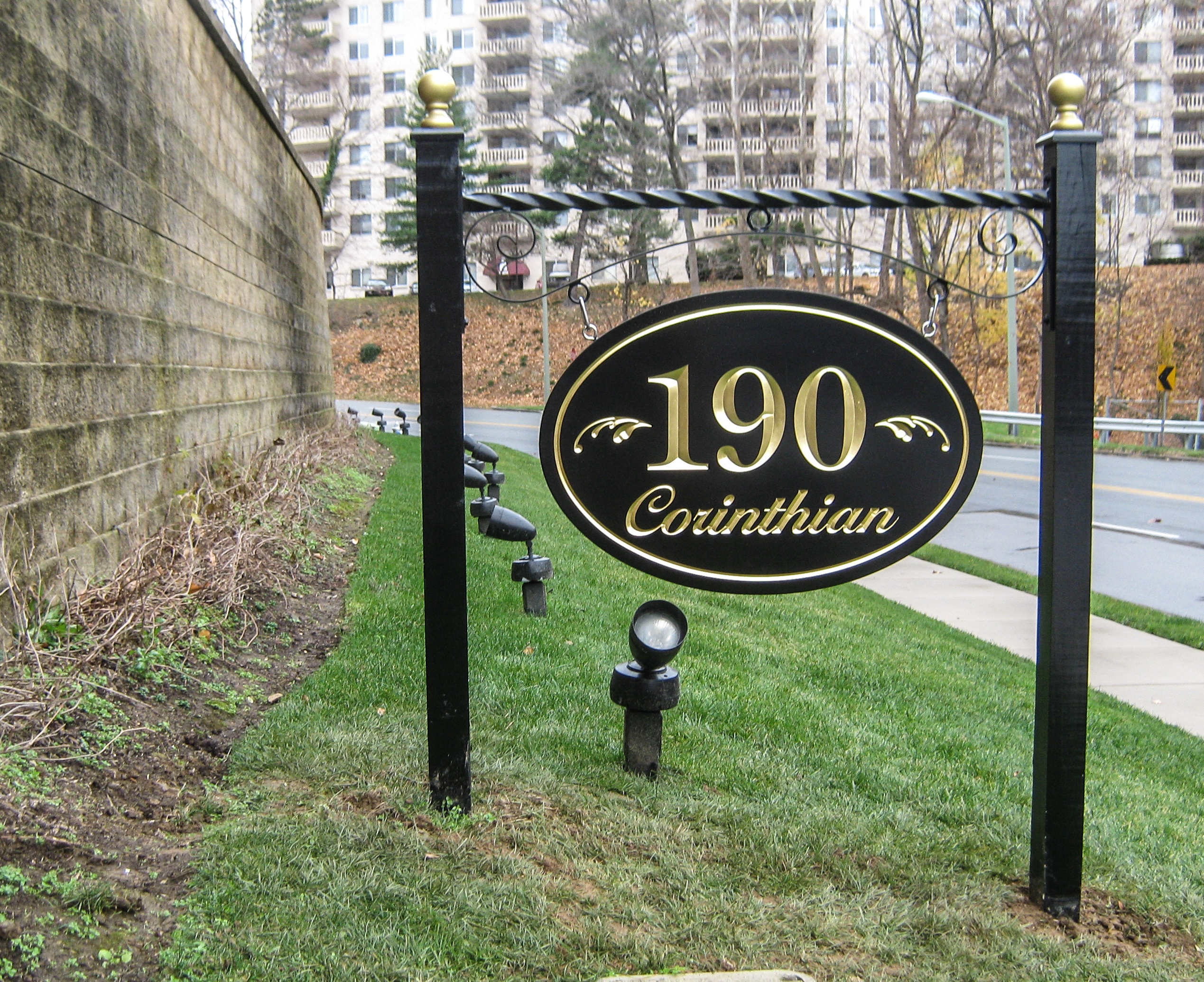 Oval, carved HDU sign suspended from a crossbar between two posts