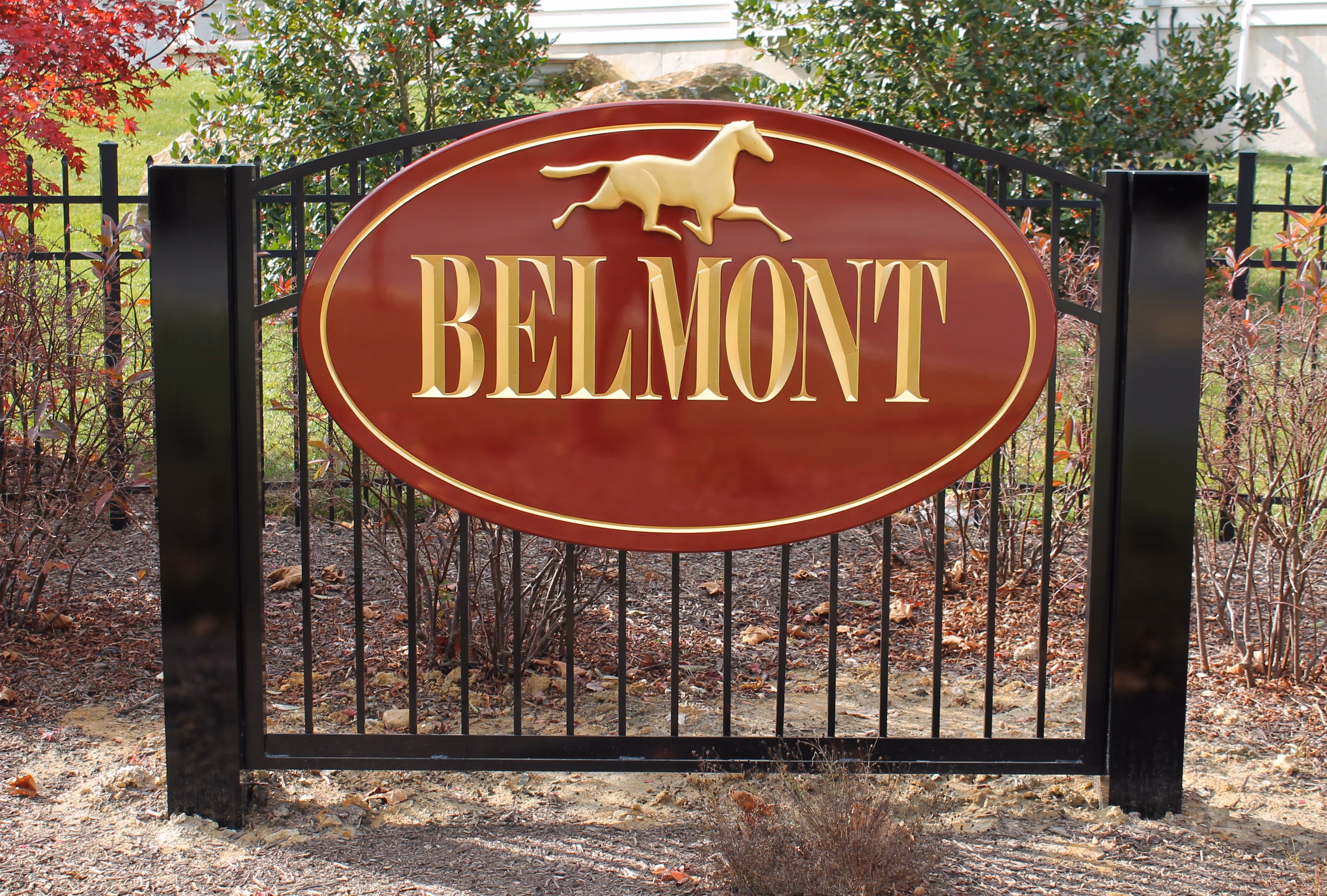 Oval, maroon carved HDU sign on a metal fence