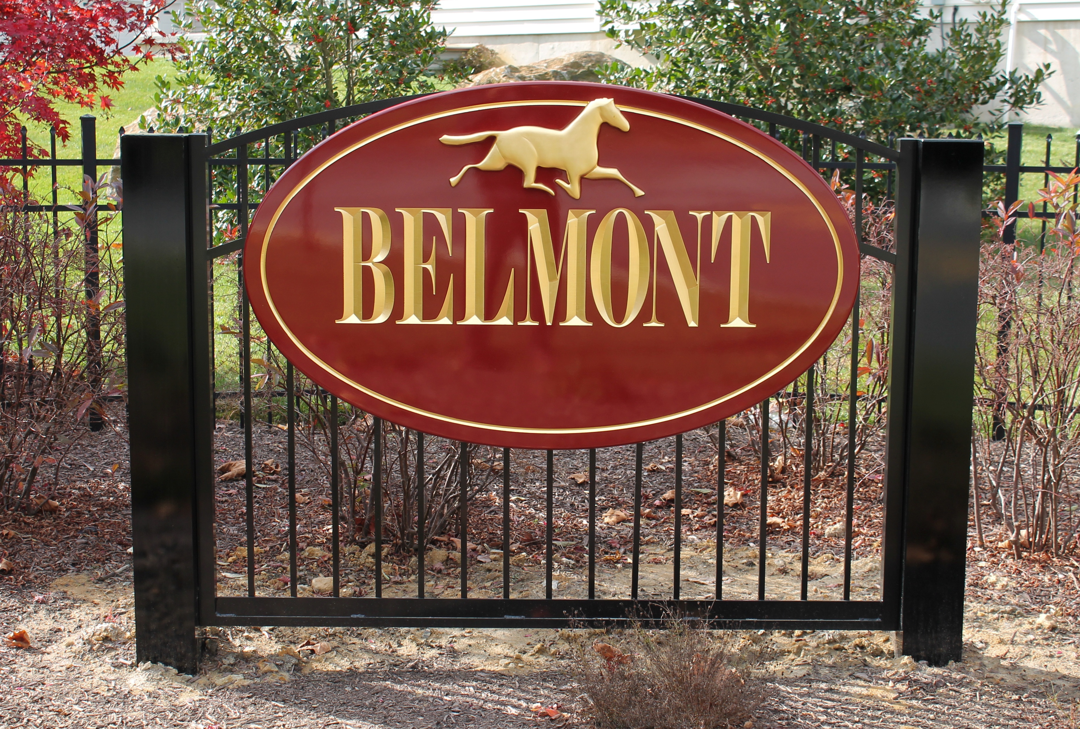 Oval, maroon carved HDU sign on a metal fence