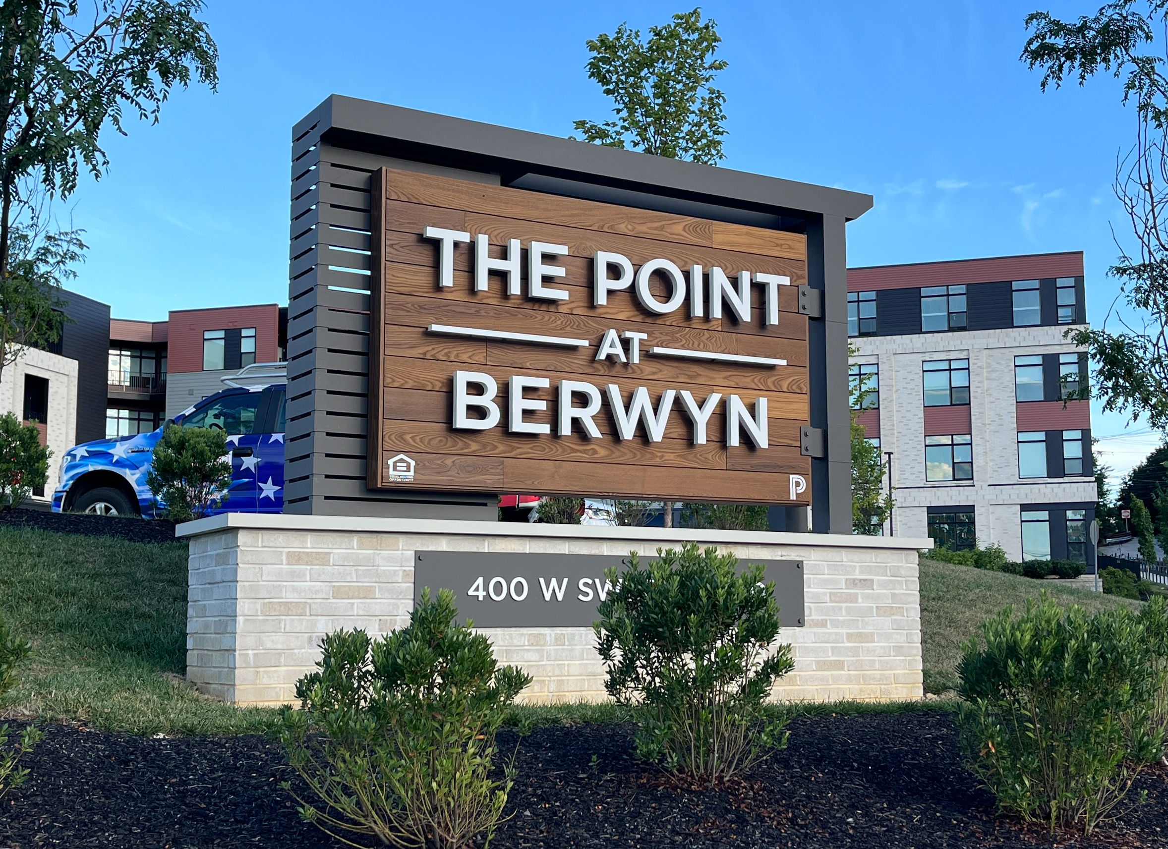 Apartment complex monument sign made of finished wood and halo-lit channel letters