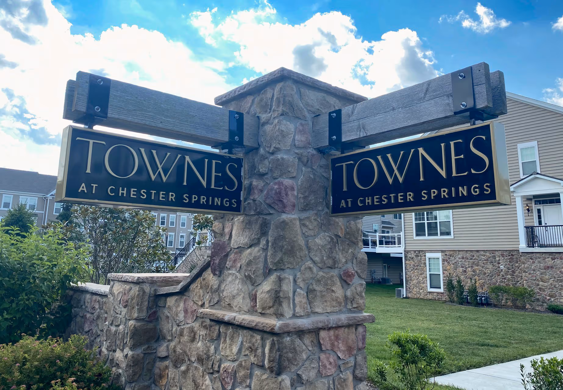 Carved HDU signs suspended from weathered beams on a monument sign