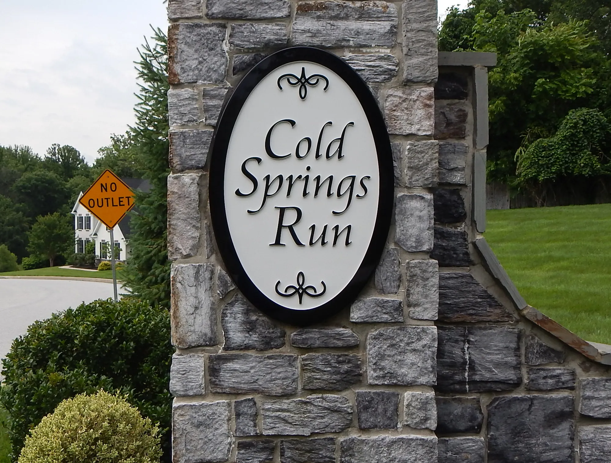 Neighborhood entrance with an oval carved HDU sign on a natural stone monument
