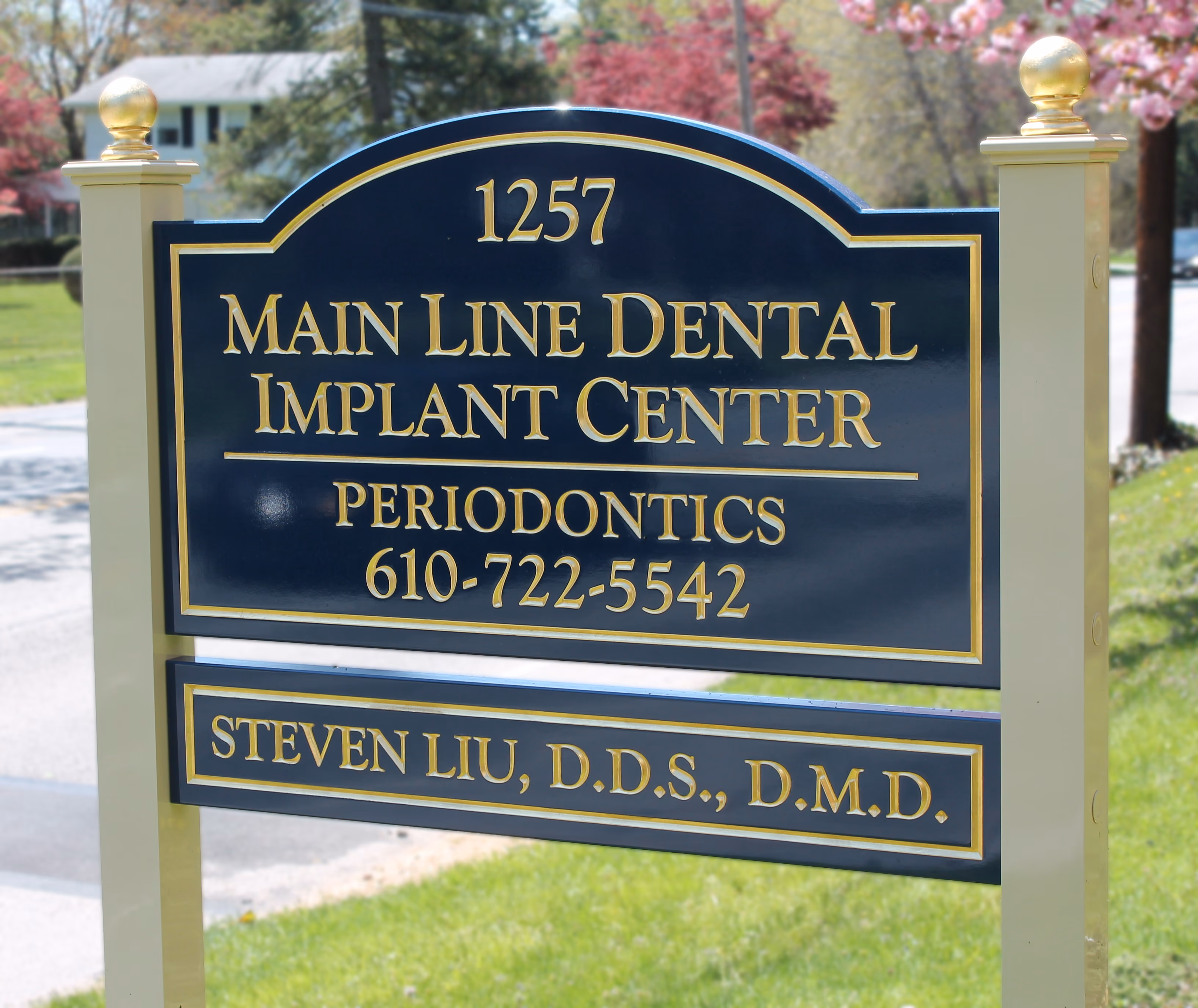 Carved HDU sign mounted between two posts with gold ball finials