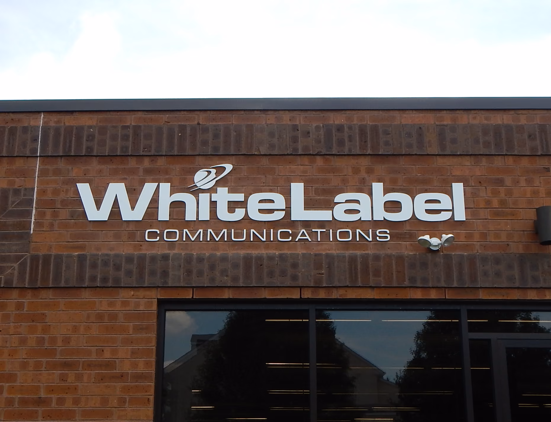 White acrylic dimensional letters mounted flush on brick above a window