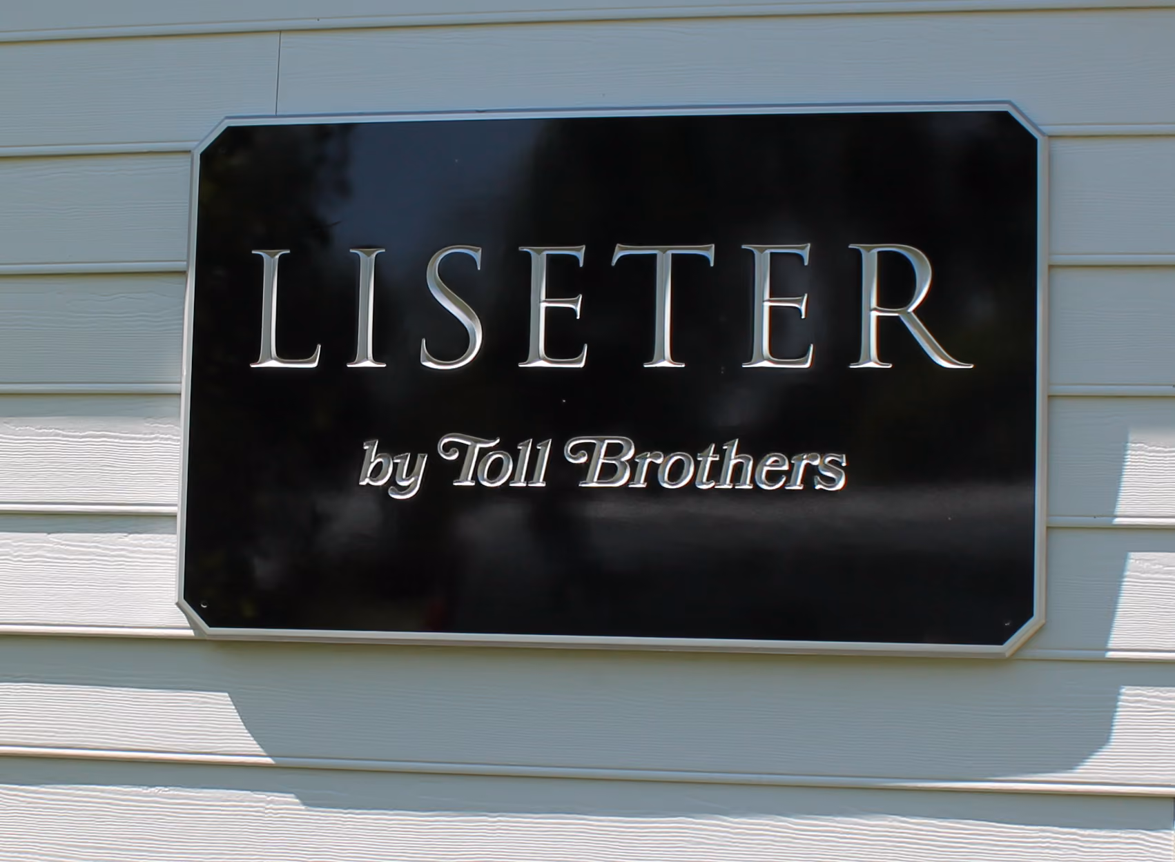 Silver and black custom carved HDU sign mounted on a buliding exterior