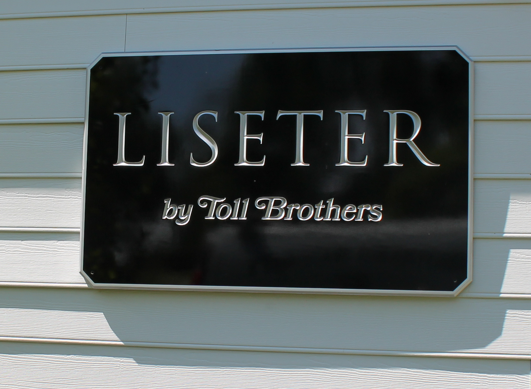 Silver and black custom carved HDU sign mounted on a buliding exterior